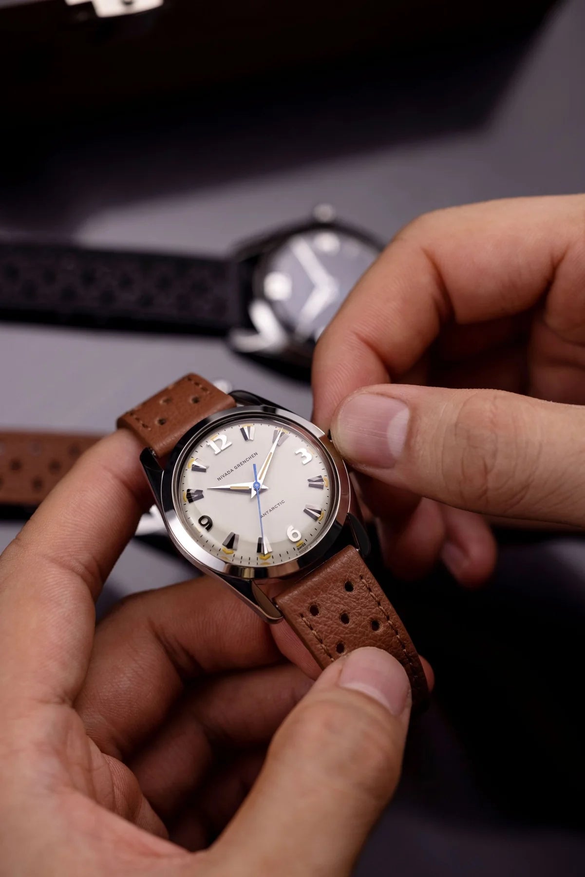 Person holding a brown leather watch with a white face Nivada Grenchen Antarctic Eggshell Dial Beige Luminova